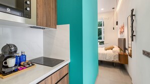 A compact hotel room with a kitchenette, a bed, a bedside table, and a view of greenery outside. - Vacation Studio 'Estudio Esquina' with Shared Terrace, Wi-Fi and Air Conditioning (Las Palmas de Gran Canaria)