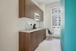 A modern kitchen with wooden cabinets, a stainless steel sink, and a window with a view of buildings.