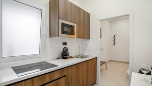 Eine moderne Küche mit Holzausstattung, einer eingebauten Mikrowelle, einer Kaffeemaschine und einem Spülbecken.