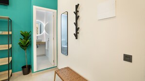 A bathroom with a mirror, a plant, a bench, and a shelf.