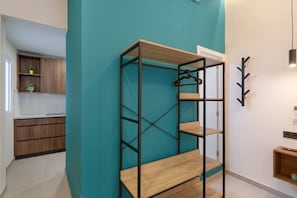 A modern kitchen with wooden cabinets, a teal accent wall, and a metal shelving unit.