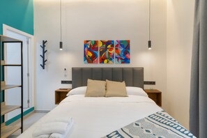 A modern hotel room with a large bed, a headboard, bedside tables, a wall art piece, and a wardrobe.