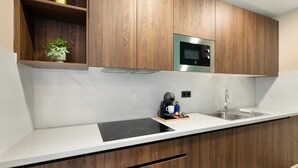 Une cuisine moderne avec des meubles en bois, un four à micro-ondes encastré, un évier en acier inoxydable et une plaque de cuisson à induction noire.