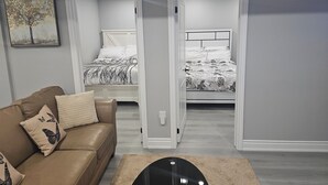 A modern bedroom with a bed, a nightstand, and a dresser. - Cozy 2 Bedrm with separate entrance
 (Kitchener)