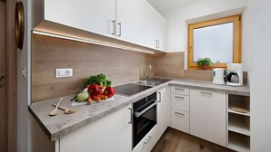 A modern kitchen with white cabinets, a wooden countertop, a built-in oven, and a window with a view. - Holiday Apartment 'Appartement Wieser A' with Mountain View, Shared Garden and Wi-Fi (Schenna)