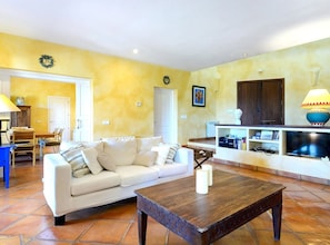A living room with a sofa, coffee table, and a TV stand with a lamp.