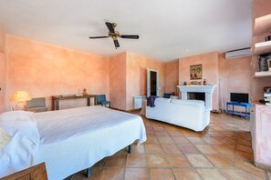 A hotel room with two beds, a ceiling fan, a fireplace, a television, and a bookshelf. - Villa 'Can Roca' with Sea Views, Wi-Fi and Air Conditioning (Illes Balears)