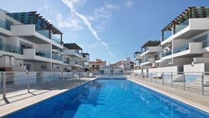 A modern hotel with a central swimming pool, multiple balconies, and a clear sky. - Apartment 'Numar Residence Aa' with Shared Pool, Wi-Fi and Air Conditioning (Vila Nova de Cacela)
