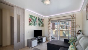 A modern living room with a flat-screen TV, a sofa, and a coffee table. - Apartment 'Numar Residence Aa' with Shared Pool, Wi-Fi and Air Conditioning (Vila Nova de Cacela)