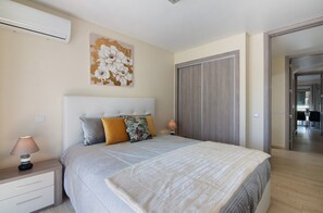 Une chambre à coucher comprenant un lit, une table de chevet, une lampe et un climatiseur fixé au mur.