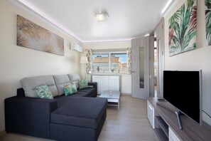 Un salon moderne doté d’un canapé d’angle, d’un téléviseur à écran plat, d’un coin repas et offrant une vue sur l’extérieur.