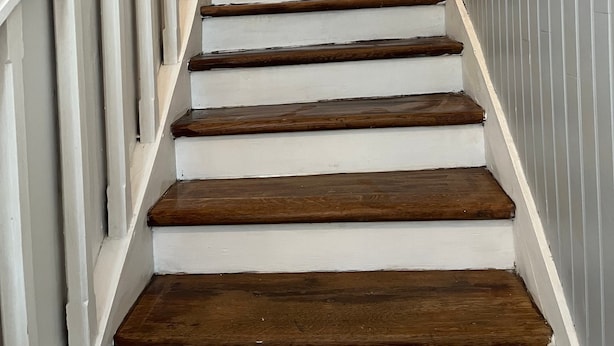 A staircase with wooden steps and white railings, leading to a landing with a lantern.