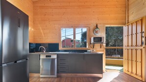 Een moderne keuken met houten wanden, een roestvrijstalen koelkast, een vaatwasser en een magnetron.