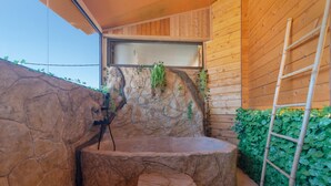 Een stenen hottub met een houten wand en een ladder.