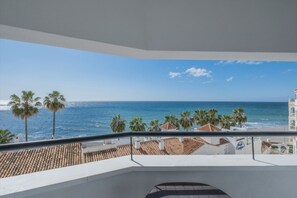Un balcon avec vue sur l’océan et les palmiers.