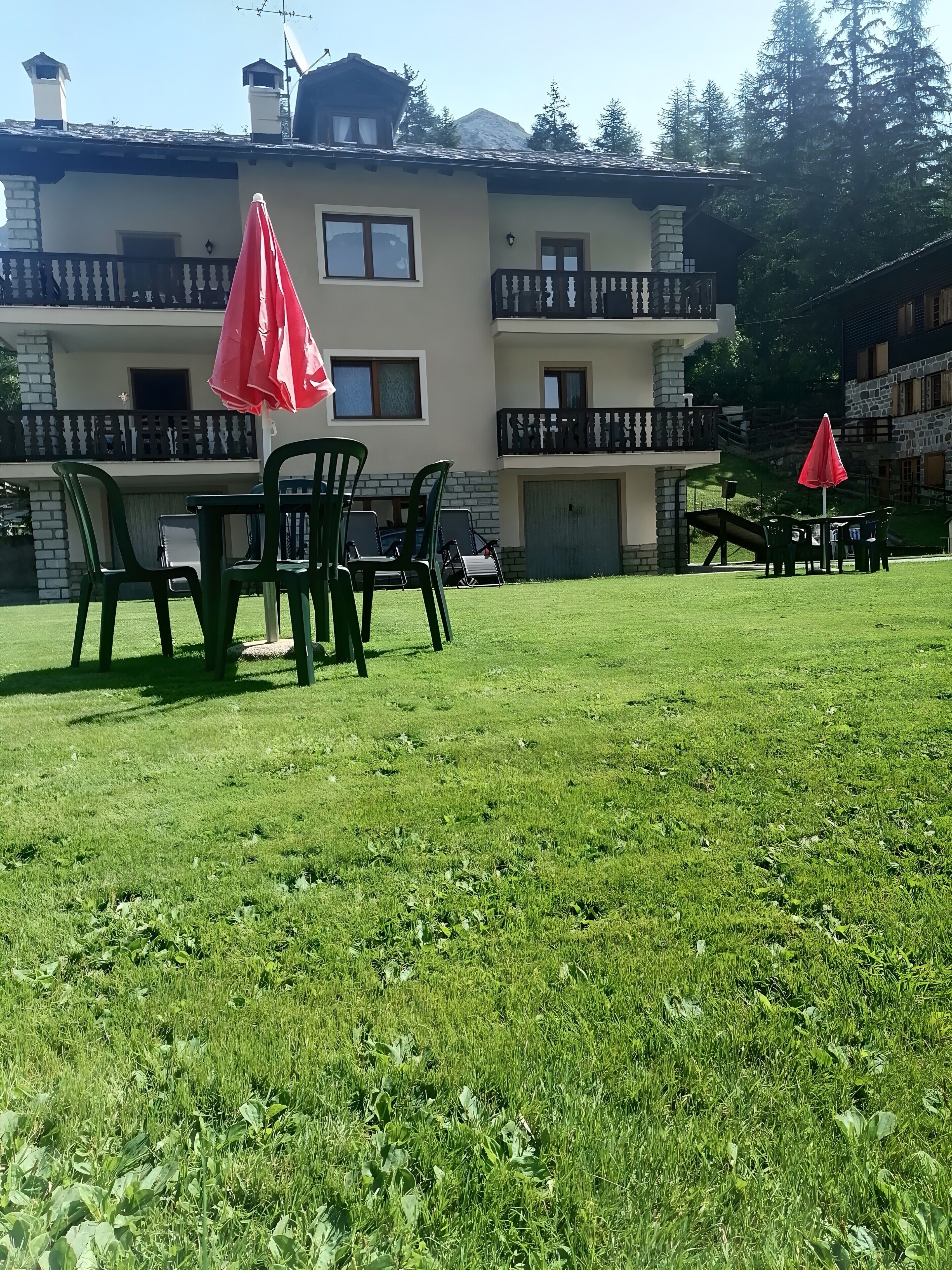 A building with a balcony, outdoor seating, and a grassy lawn.