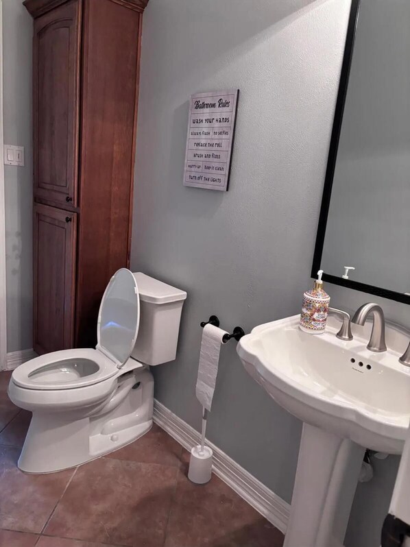 A bathroom with a toilet, sink, and a sign listing bathroom rules.