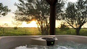 A hot tub with a view of a sunset and trees.