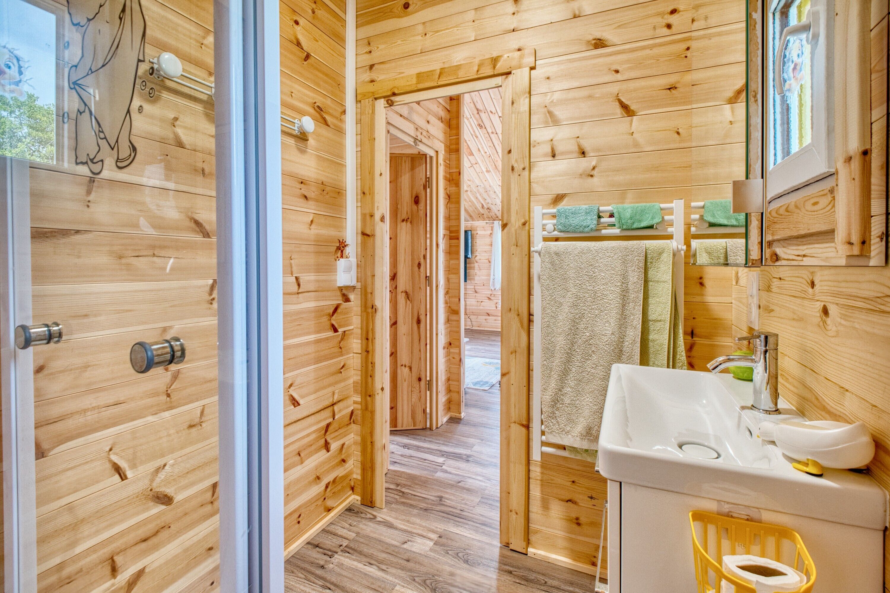 A wooden interior with a bathroom featuring a sink, mirror, and towel rack.