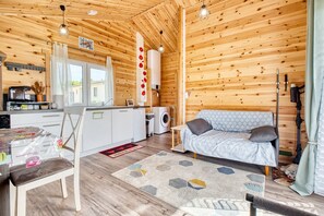 A wooden interior with a kitchen, a sofa, and a dining area.