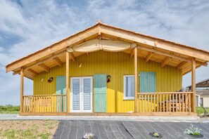 A yellow wooden building with a porch, two doors, and a small window.