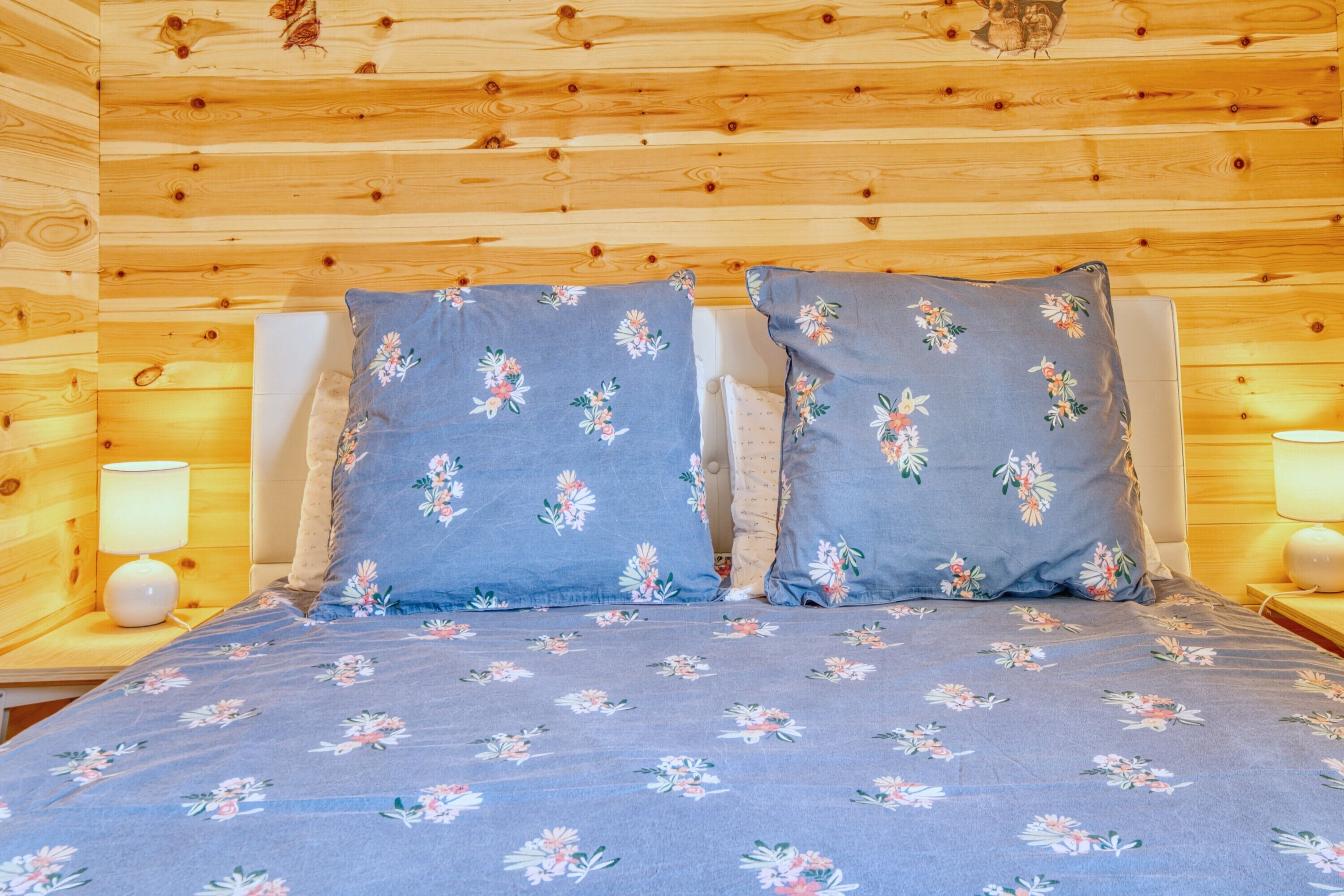 A wooden-paneled room with a bed, two pillows, and two bedside lamps.