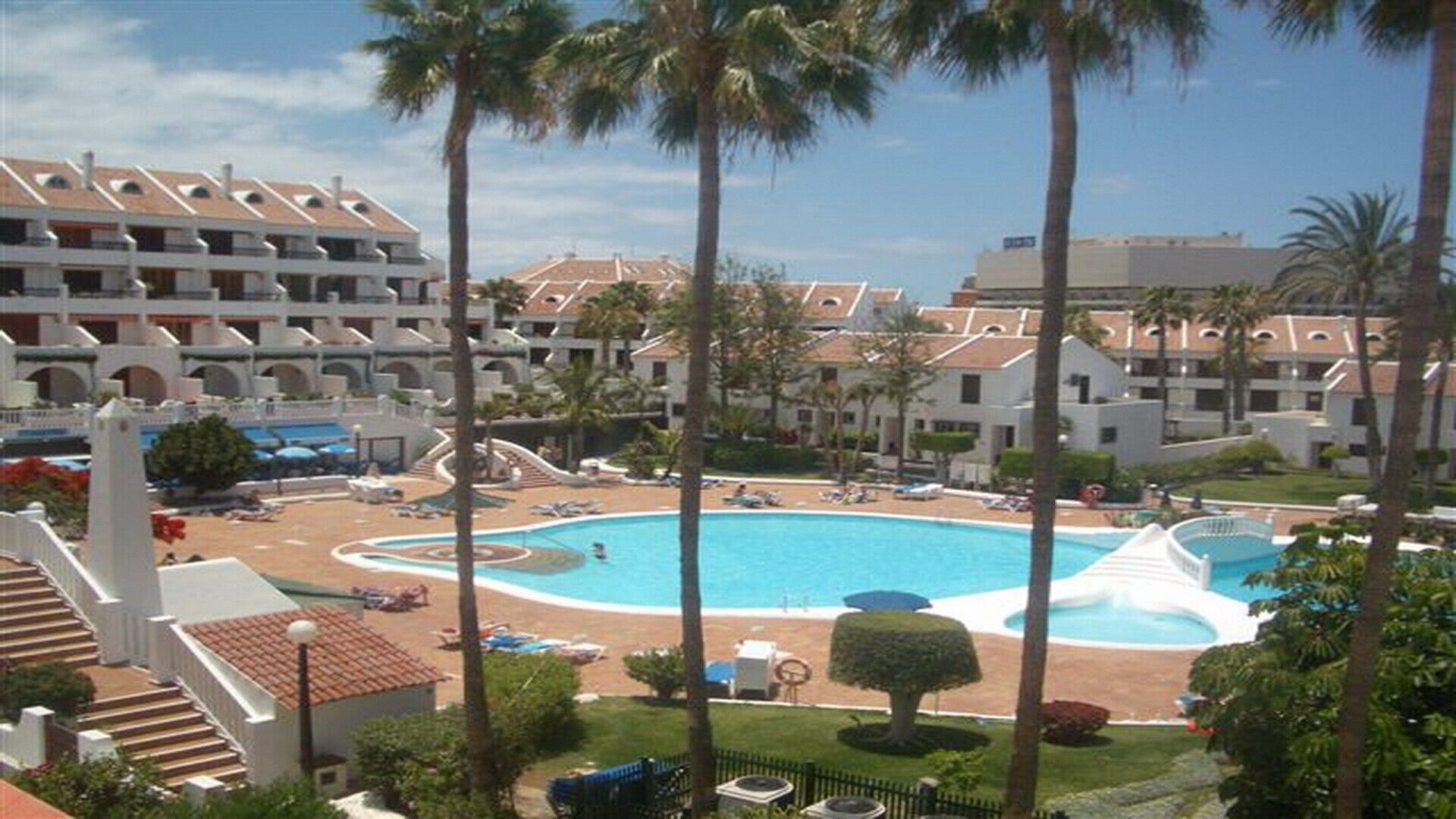Ein Hotel mit Pool, Palmen und Strand.