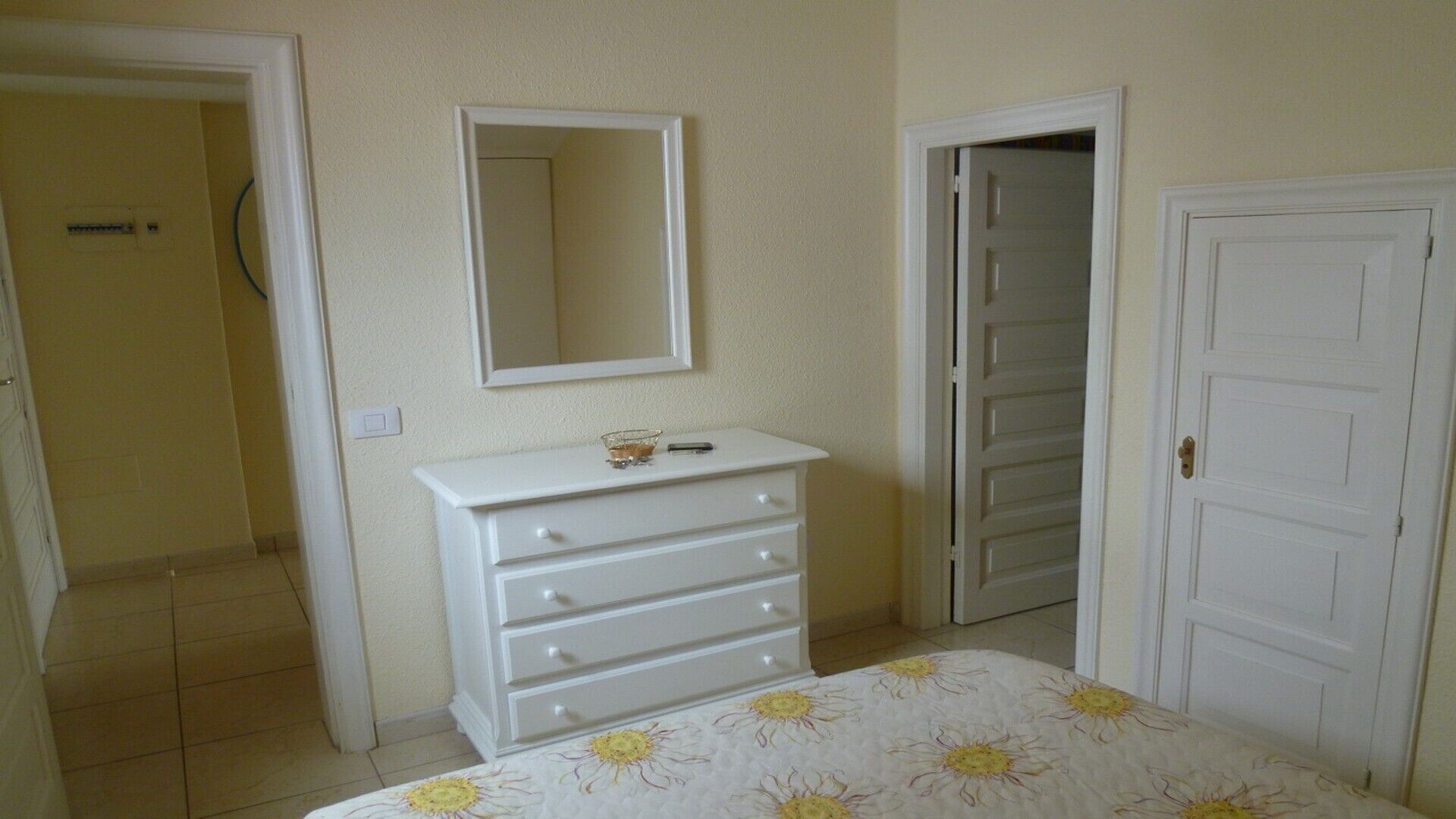 Un dormitorio con una cama, un tocador, un espejo y dos puertas.