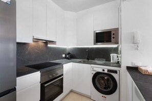 A compact kitchen with white cabinets, a built-in microwave, a washing machine, and a sink. - Holiday Apartment "Rincon Tropical" with Sea View, Shared Pool & Wi-Fi (Candelaria)