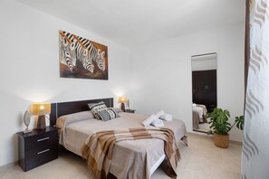 A bedroom with a bed, nightstands, a mirror, a zebra painting, and a potted plant. - Holiday Apartment "Rincon Tropical" with Sea View, Shared Pool & Wi-Fi (Candelaria)