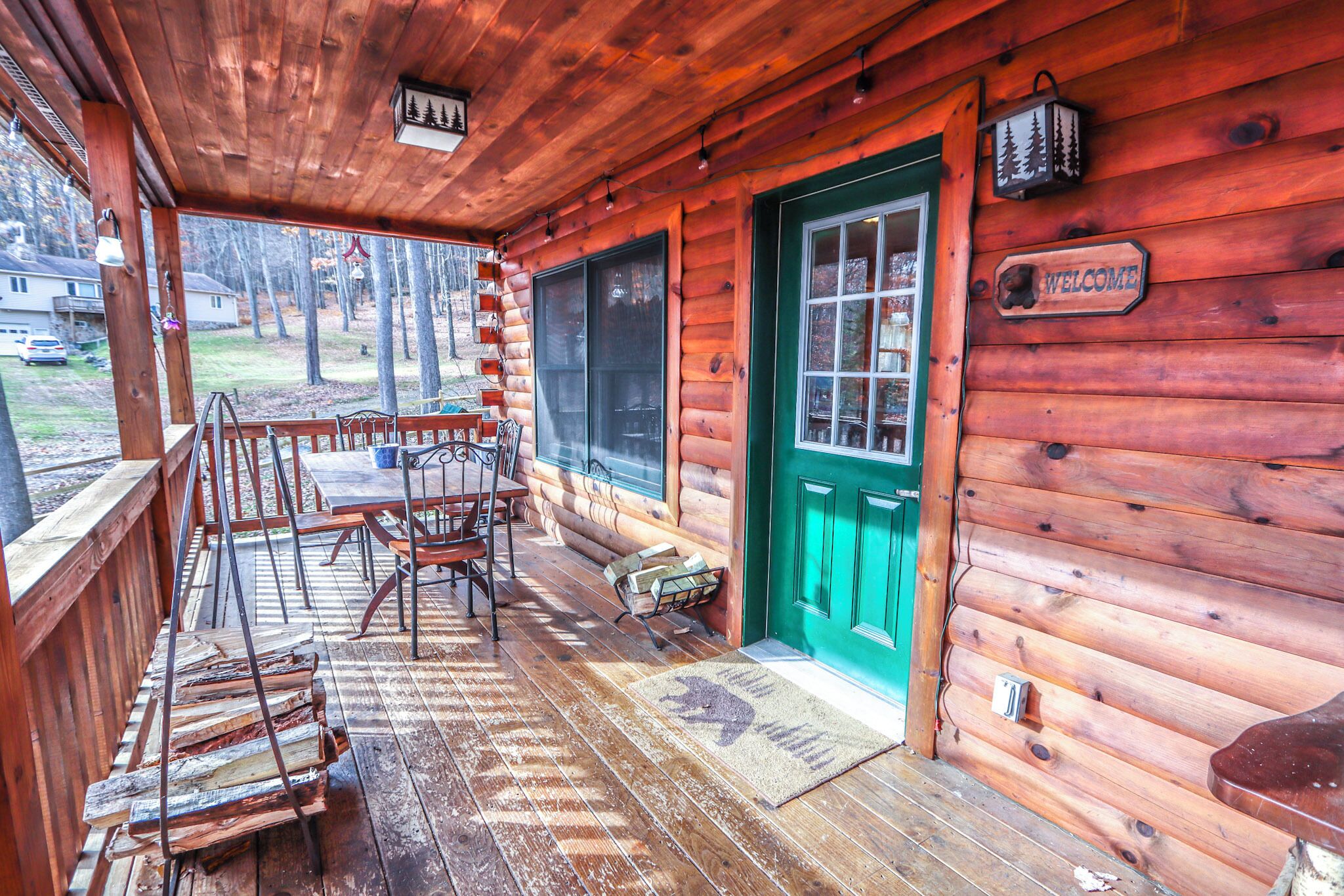 Une cabane en bois avec un porche, une porte verte et une pancarte indiquant « Bienvenue ».