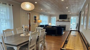 A dining area with a wooden table and chairs, a bar area with a pool table, and a fireplace. - Country BEACH home! (Southold)