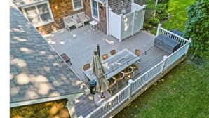 A deck with outdoor seating, a table, and a grill. - Country BEACH home! (Southold)