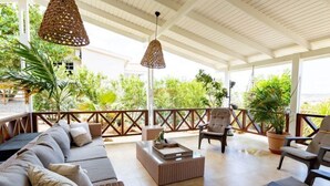 A covered outdoor seating area with wicker furniture, a coffee table, and hanging lights. - Tropical Luxury with Private Pool & Recreational Opportunities! (Willemstad)