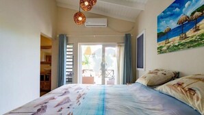 A bedroom with a bed, a painting of a beach scene, and an air conditioning unit on the wall. - Tropical Luxury with Private Pool & Recreational Opportunities! (Willemstad)