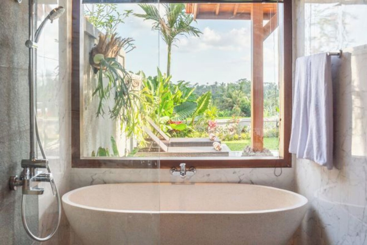 A bathroom with a large window, a bathtub, and a shower.