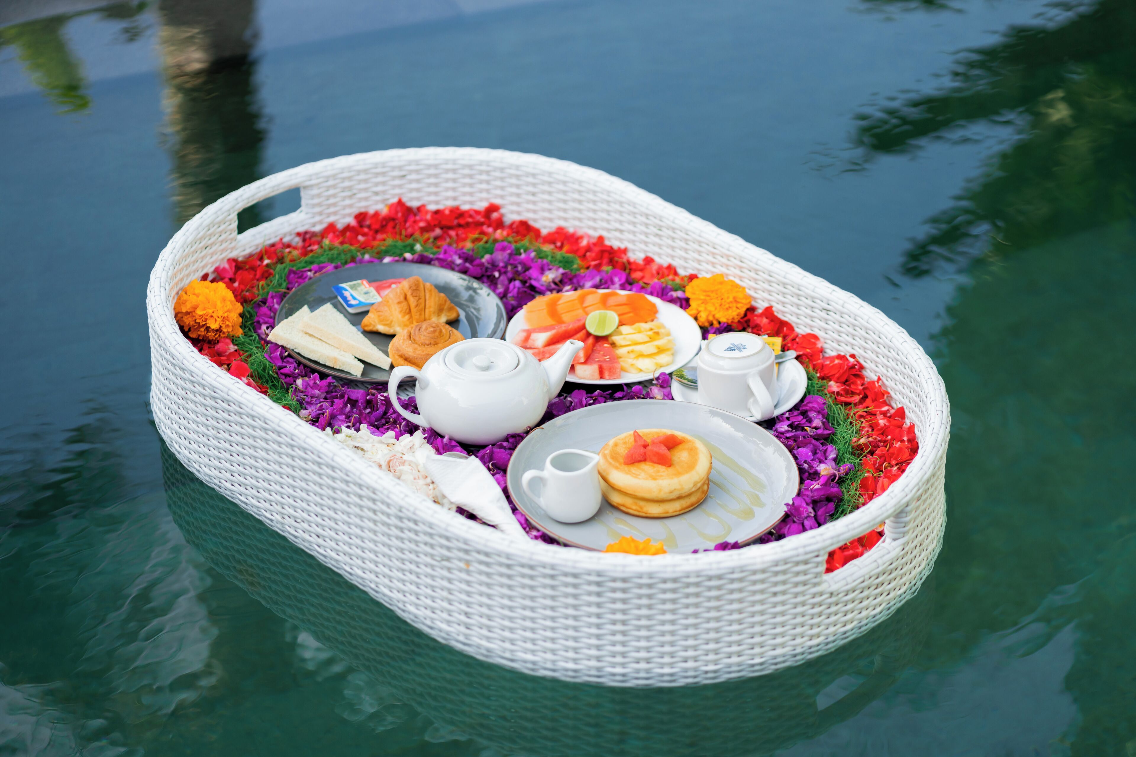 A floating basket with food and drinks on a body of water.