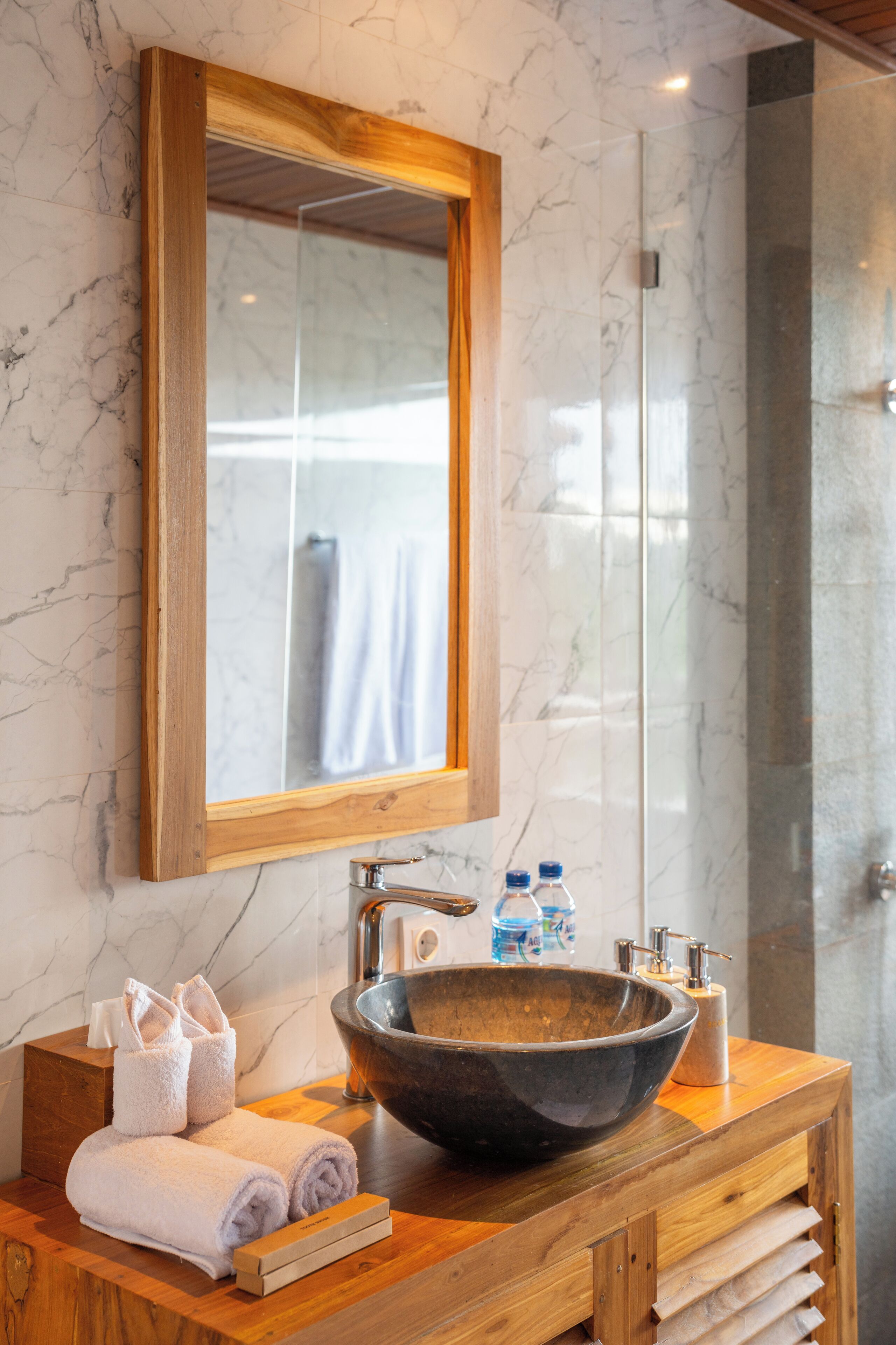 Une salle de bain avec un meuble-lavabo en bois, un grand lavabo en forme de cuve et un miroir au-dessus.