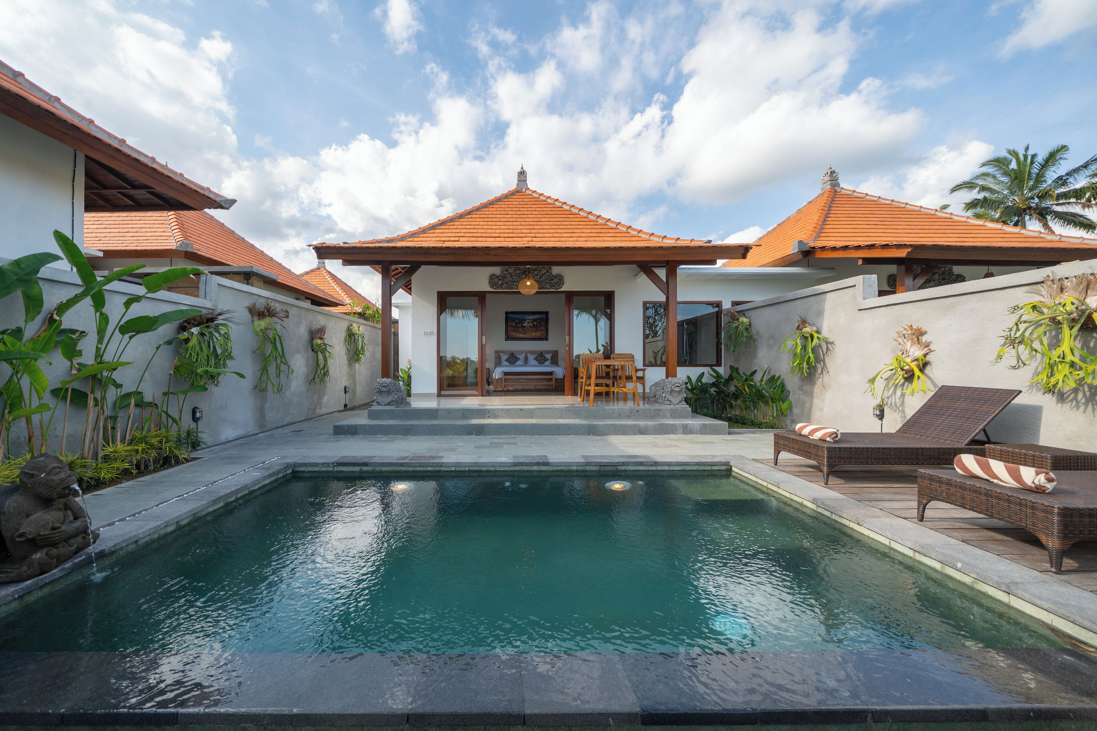 A pool area with lounge chairs and a small seating area.