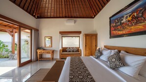 A spacious bedroom with a large bed, wooden headboard, and a painting of horses. - Kaki Uma Villa (Sebatu)