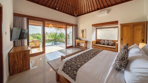 A spacious bedroom with a large bed, wooden headboard, a TV, and a sliding glass door leading to a balcony. - Kaki Uma Villa (Sebatu)