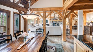 A spacious wooden dining area with a long table, chairs, and a chandelier.