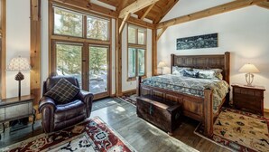 A spacious bedroom with a large bed, a leather armchair, and a wooden chest of drawers.
