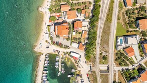 Vista aèria d'una zona costanera amb un port esportiu, edificis residencials i una via fèrria.