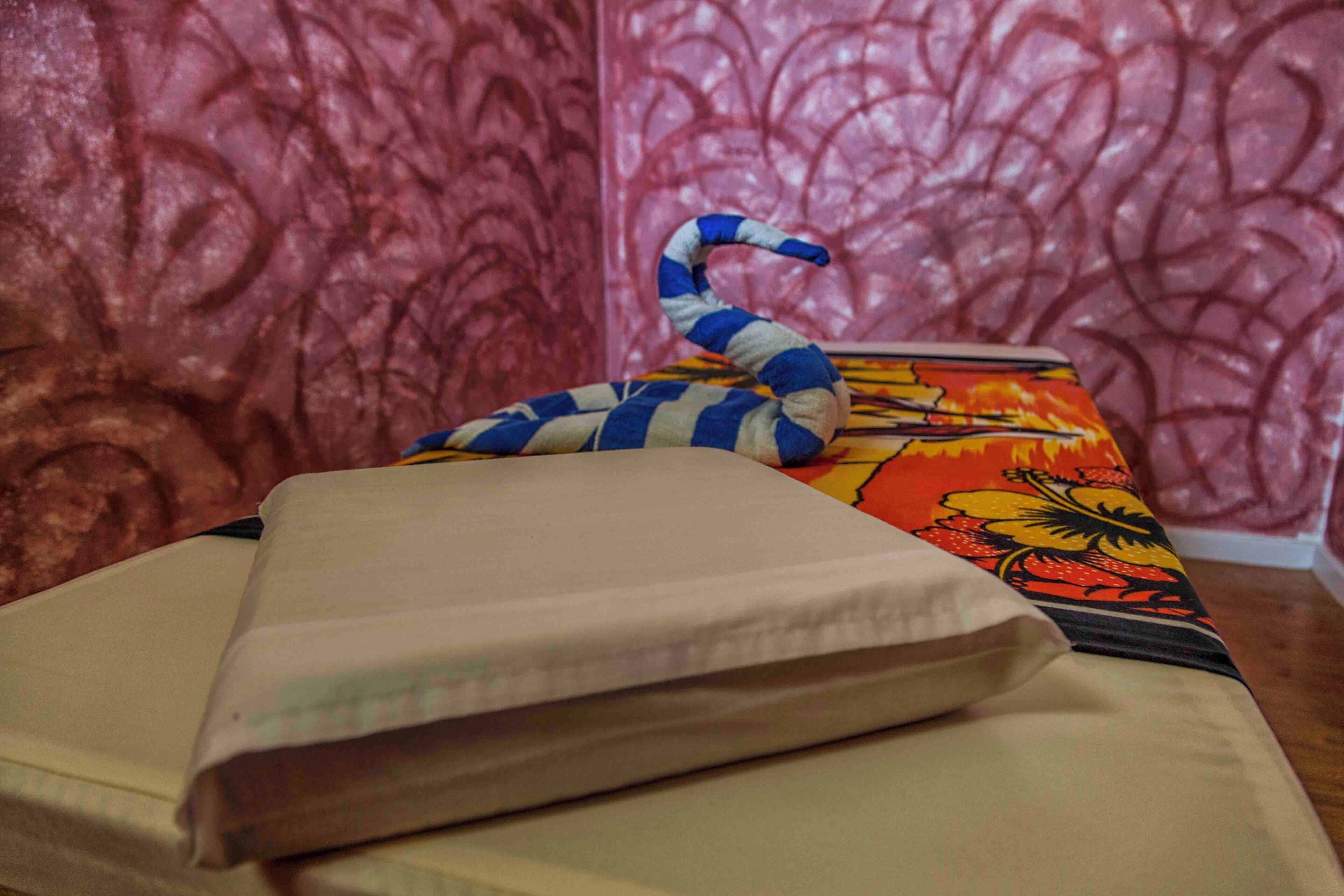 A bed with a striped pillow and a colorful blanket.