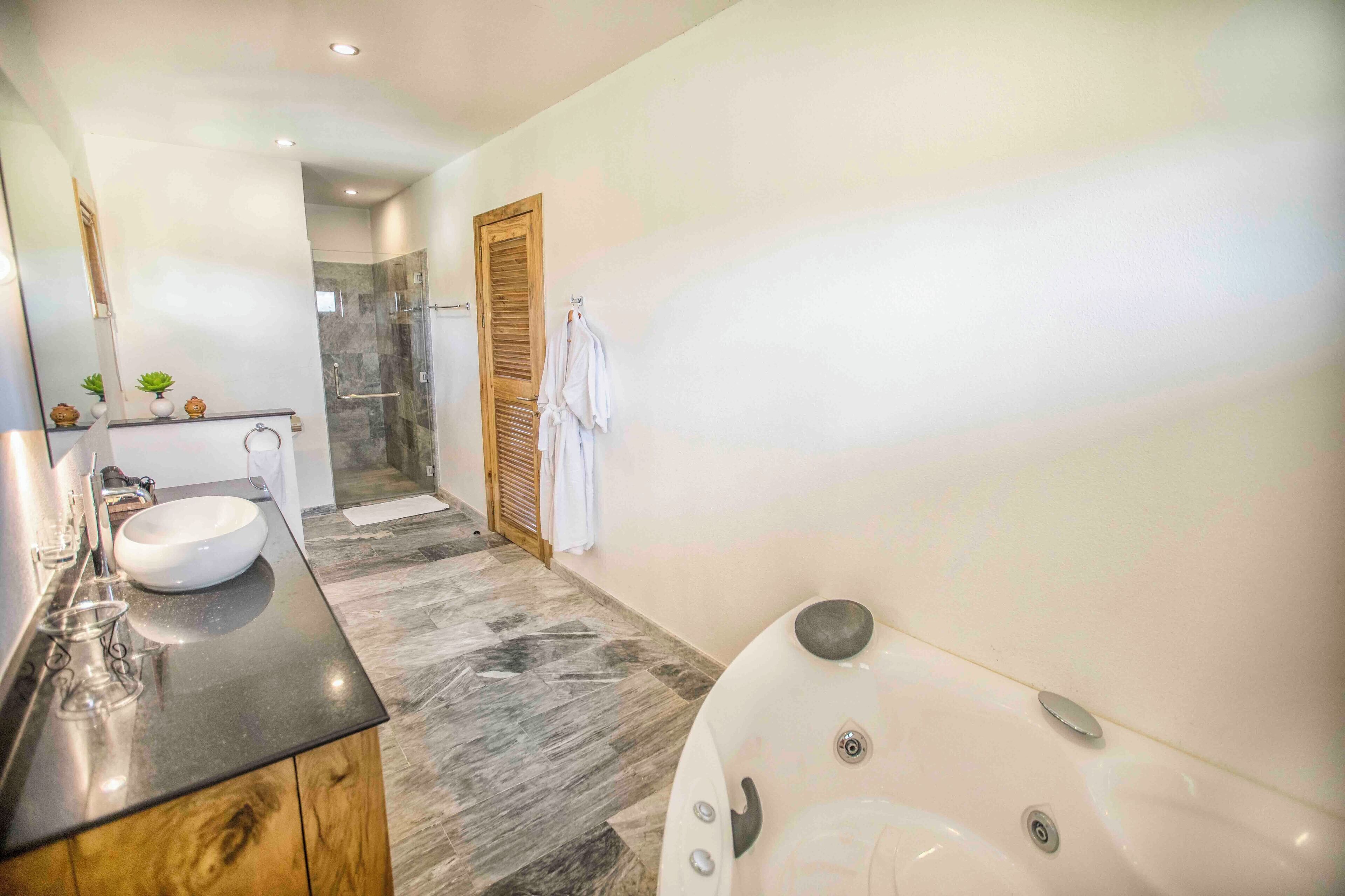 A modern bathroom with a large bathtub, a vanity with a sink, and a shower area.