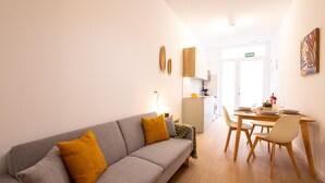 Una sala moderna con un sofá gris, una mesa de comedor de madera y sillas.