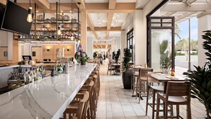Eine moderne Bar mit Marmorplatte, Holzhockern und einer Auswahl an Flaschen und Gläsern.