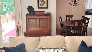 A beige sofa with blue cushions, a wooden cabinet, a dining table with chairs, and a chandelier. - Pollys Place for bird lovers - Private, Close to Gallatin-Sleeps 10-Pet Friendly (Portland)
