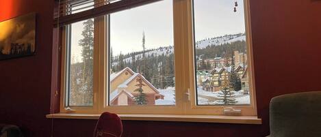 A room with a large window overlooking a snowy landscape with buildings.